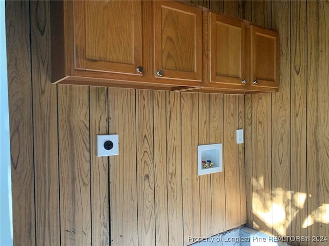 clothes washing area featuring cabinets, wood walls, hookup for a washing machine, and electric dryer hookup