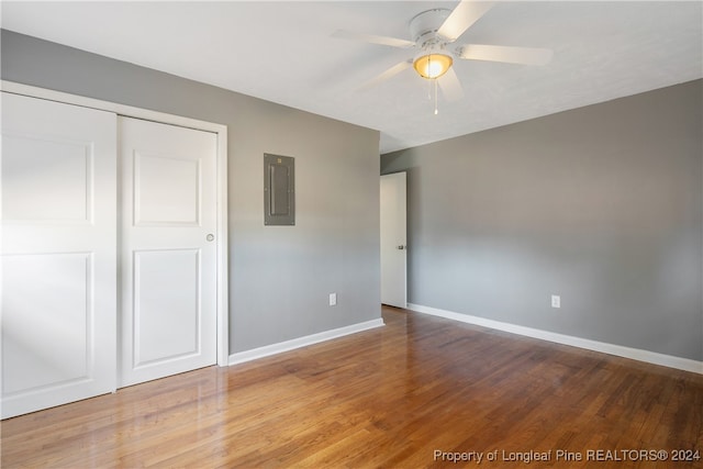 unfurnished bedroom featuring hardwood / wood-style flooring, ceiling fan, electric panel, and a closet