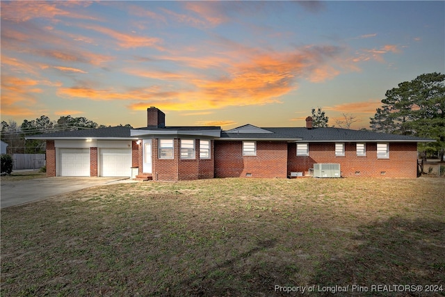 view of front of property with a lawn, central AC unit, and a garage