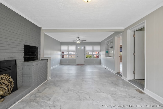 unfurnished living room featuring ceiling fan, a brick fireplace, built in features, a textured ceiling, and ornamental molding