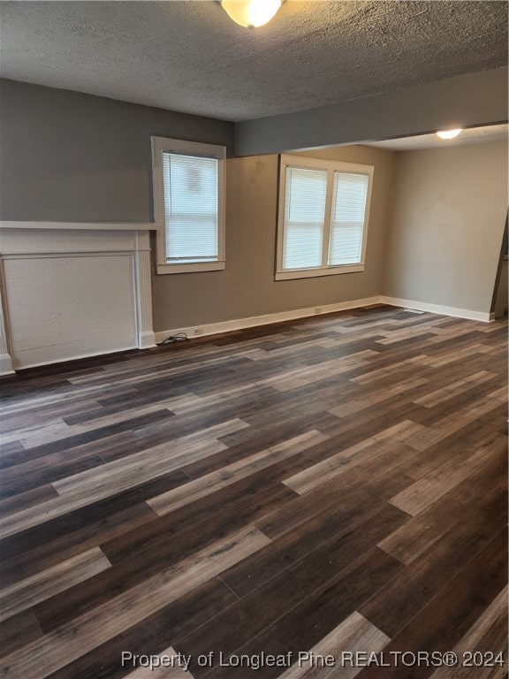 spare room with a textured ceiling and dark wood-type flooring