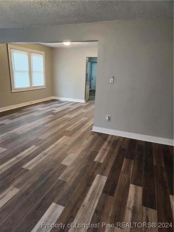 unfurnished room featuring a textured ceiling and dark hardwood / wood-style floors