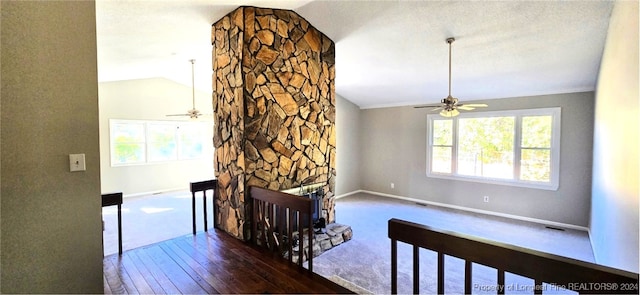 living room featuring vaulted ceiling, ceiling fan, dark wood-type flooring, crown molding, and a fireplace