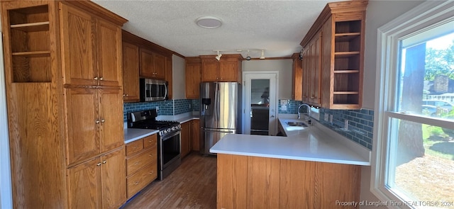 kitchen featuring dark hardwood / wood-style floors, kitchen peninsula, backsplash, and appliances with stainless steel finishes