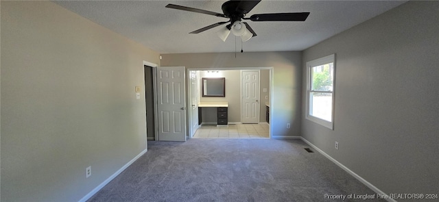 empty room with a textured ceiling, light colored carpet, and ceiling fan