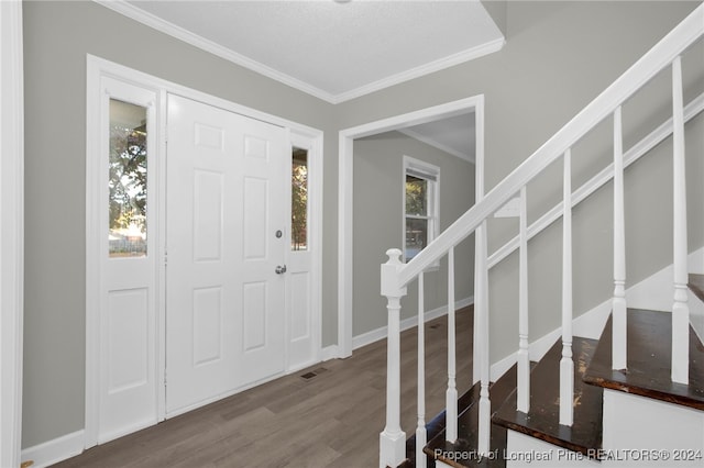 entrance foyer with wood-type flooring, a textured ceiling, and ornamental molding