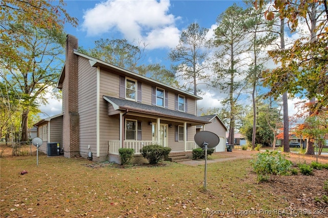 view of front facade featuring a front lawn, an outbuilding, central AC unit, covered porch, and a garage