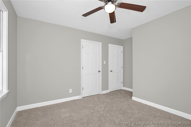 interior space with a textured ceiling, carpet floors, and ceiling fan