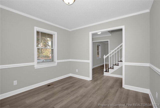 empty room featuring hardwood / wood-style floors, a textured ceiling, and ornamental molding