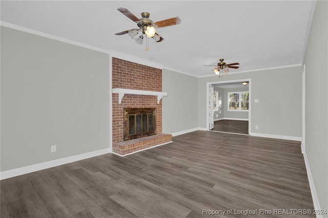 unfurnished living room with ceiling fan, ornamental molding, dark wood-type flooring, and a brick fireplace