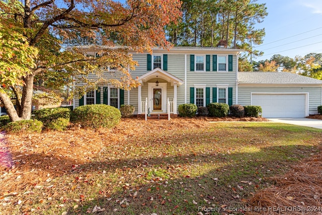 colonial-style house featuring a garage and a front lawn