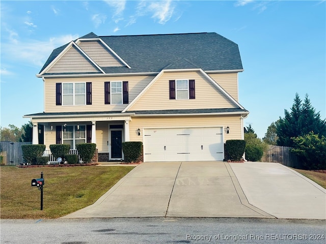 view of front of home with a porch, a front yard, and a garage