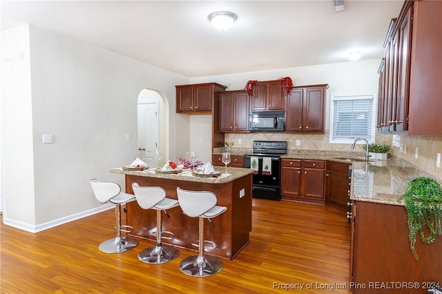 kitchen featuring black appliances, a center island, sink, and dark wood-type flooring