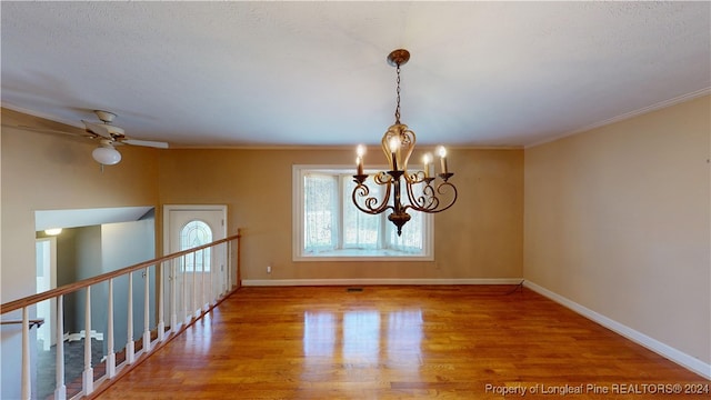 unfurnished room featuring a chandelier, wood-type flooring, a textured ceiling, and ornamental molding