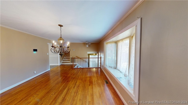 empty room with hardwood / wood-style floors, ceiling fan with notable chandelier, and ornamental molding