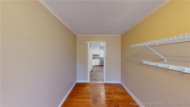 hallway featuring wood-type flooring, a textured ceiling, and ornamental molding