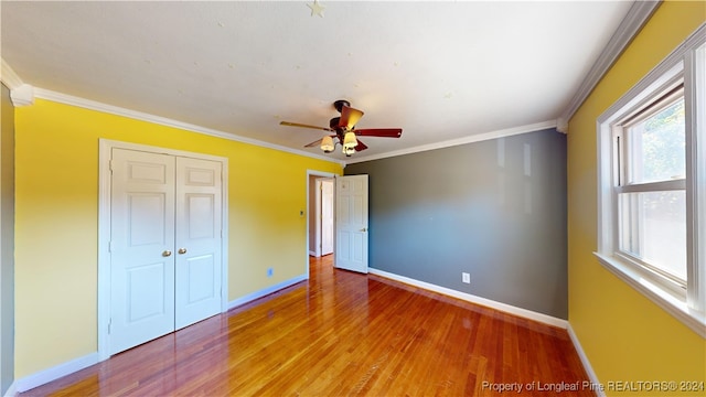 unfurnished bedroom with wood-type flooring, crown molding, and a closet