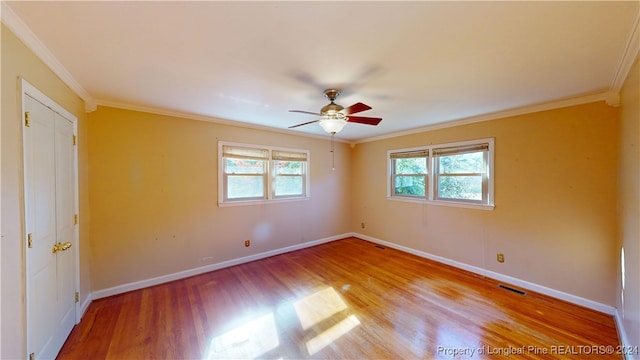 empty room with ceiling fan, light wood-type flooring, and ornamental molding