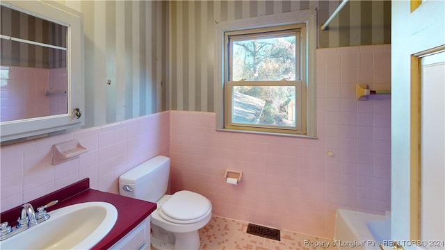 full bathroom featuring vanity, toilet, tile walls, and independent shower and bath