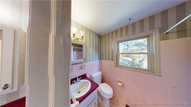 bathroom with vanity, tile walls, and toilet