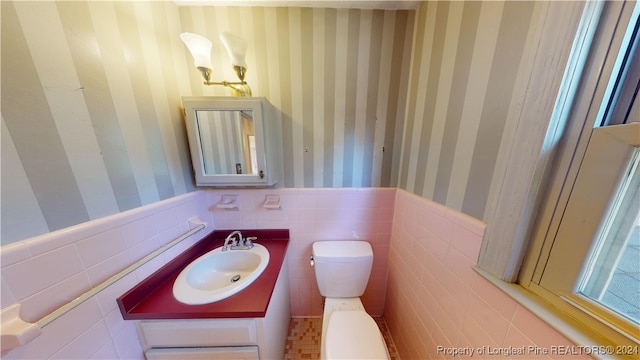 bathroom featuring vanity, toilet, and tile walls