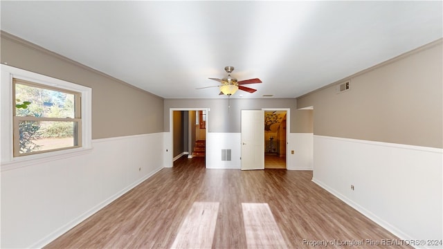 empty room with hardwood / wood-style flooring, ceiling fan, and ornamental molding