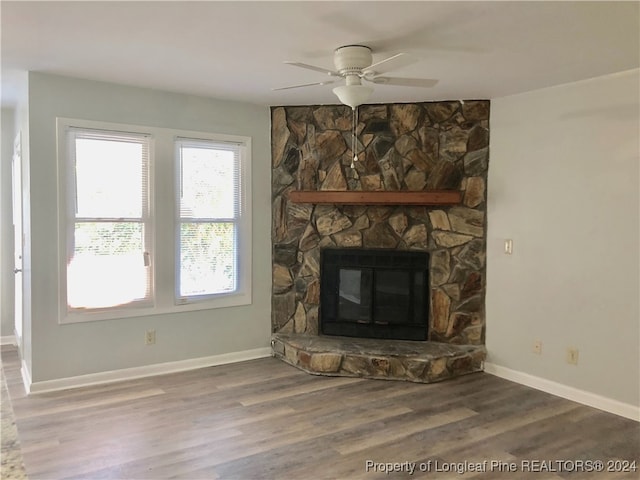 unfurnished living room featuring ceiling fan, a stone fireplace, and wood-type flooring