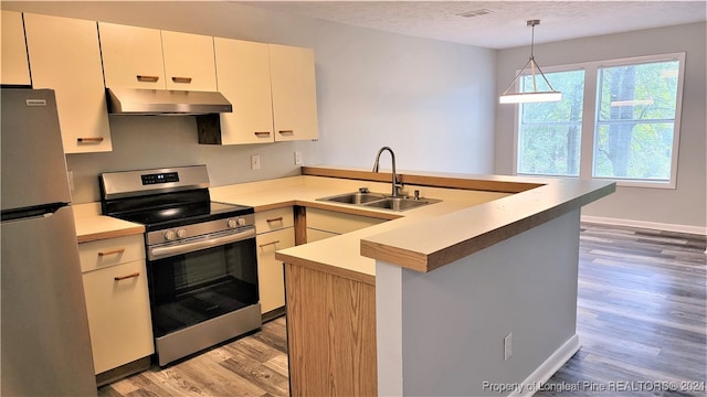 kitchen featuring a textured ceiling, stainless steel appliances, sink, light hardwood / wood-style flooring, and hanging light fixtures