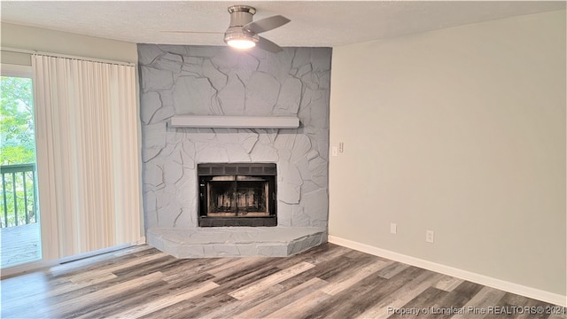 room details featuring a fireplace, ceiling fan, hardwood / wood-style floors, and a textured ceiling