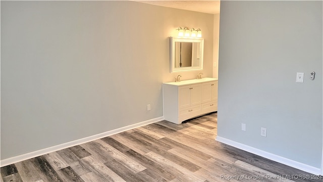 interior space with connected bathroom, light hardwood / wood-style floors, and sink