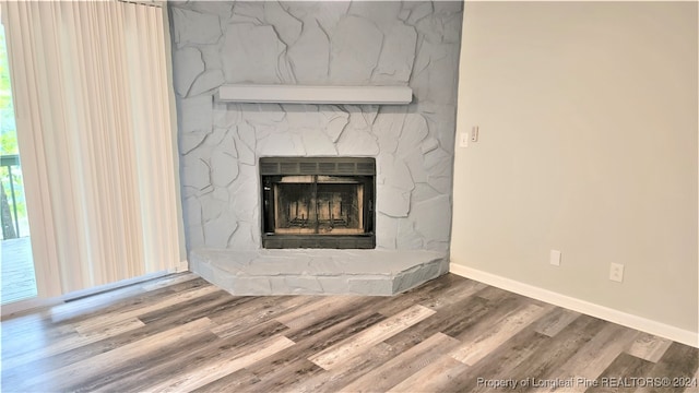 interior details featuring wood-type flooring and a stone fireplace