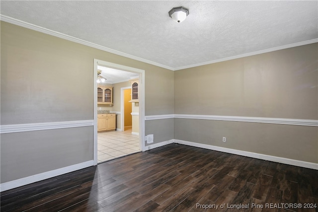 spare room featuring a textured ceiling, dark hardwood / wood-style floors, and crown molding