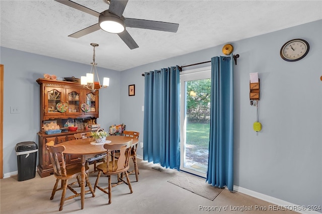 dining space featuring ceiling fan with notable chandelier and a textured ceiling