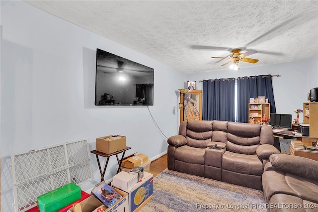 living room with a textured ceiling, hardwood / wood-style flooring, and ceiling fan