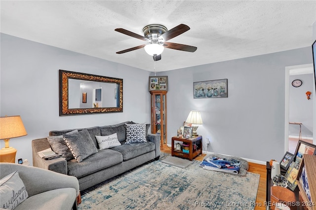 living room featuring wood-type flooring, a textured ceiling, and ceiling fan