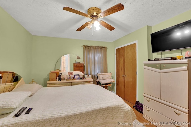 bedroom featuring ceiling fan, light hardwood / wood-style floors, a textured ceiling, and a closet