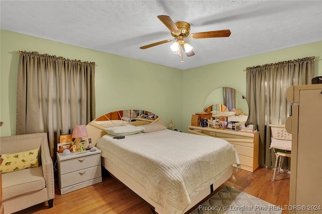 bedroom with ceiling fan, a textured ceiling, and light wood-type flooring