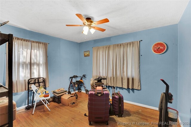 misc room with ceiling fan, a textured ceiling, and hardwood / wood-style flooring