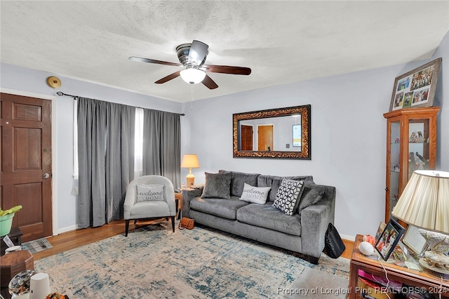 living room with ceiling fan, a textured ceiling, and hardwood / wood-style flooring