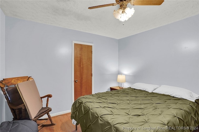 bedroom with a textured ceiling, light wood-type flooring, and ceiling fan