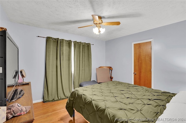 bedroom with light wood-type flooring, a textured ceiling, and ceiling fan