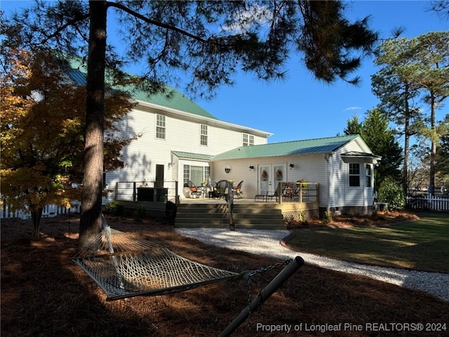 rear view of property featuring a deck, a yard, and french doors