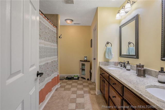 bathroom with vanity, a textured ceiling, and walk in shower