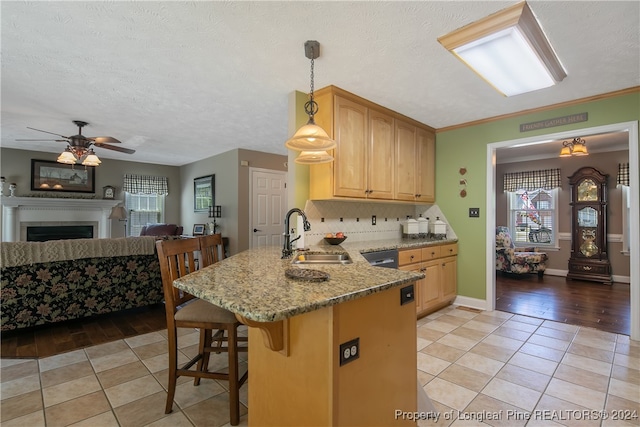 kitchen featuring a kitchen breakfast bar, light wood-type flooring, pendant lighting, and sink