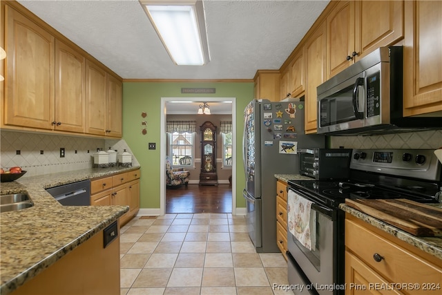 kitchen featuring tasteful backsplash, ornamental molding, stainless steel appliances, stone counters, and light tile patterned flooring