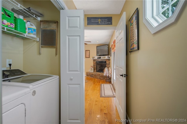 washroom featuring a fireplace, light hardwood / wood-style flooring, and washer and dryer