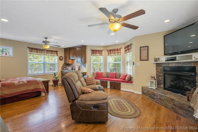 living room featuring a fireplace, light wood-type flooring, and ceiling fan