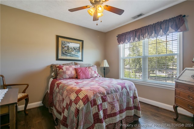 bedroom with a textured ceiling, ceiling fan, and dark wood-type flooring