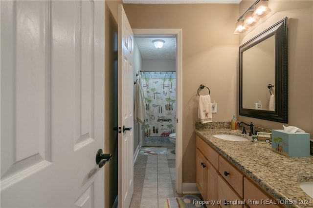 bathroom with a shower with curtain, tile patterned flooring, a textured ceiling, toilet, and vanity