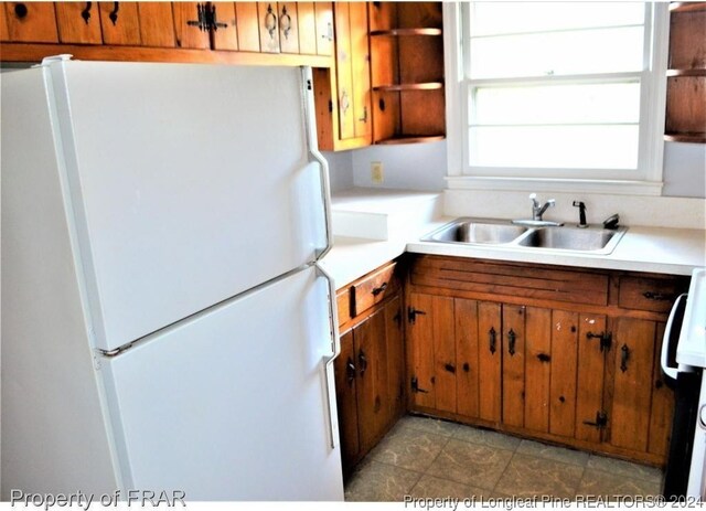 kitchen featuring sink, light tile patterned flooring, stove, and white refrigerator